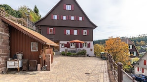 Un bâtiment traditionnel doté d’un toit en pente, d’un escalier en pierre et d’une cour pavée.