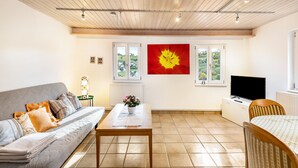 A living room with a sofa, a coffee table, a TV, and a window with a view. - Appartment Apothekerstube (Altensteig)