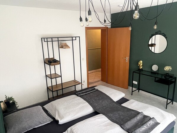 A bedroom with a bed, a bedside table, a mirror, and a wardrobe. - Apartment Fewo Lago di Costanza 2 with Private Garden, Lounge & Balcony (Friedrichshafen)