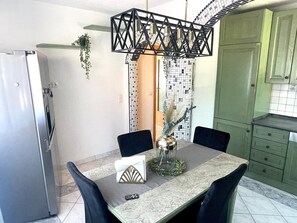 A dining area with a table, chairs, a chandelier, and a refrigerator. - Apartment Fewo Lago di Costanza 2 with Private Garden, Lounge & Balcony (Friedrichshafen)