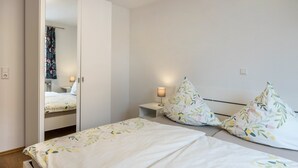 Un dormitorio con cama, mesita de noche, lámpara y espejo.