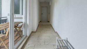 Un pasillo estrecho con un banco de madera y una mesa a la izquierda, que conduce a una puerta al final.