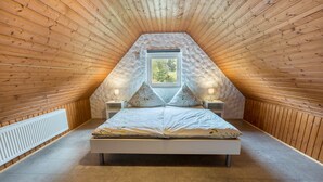 A bedroom with a sloped ceiling, a window, a bed, and bedside lamps. - Apartment 'Ferienwohnung 2, 80qm' with Mountain View, Shared Garden and Wi-Fi (Rosswangen)