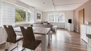 A modern kitchen with a dining area, wooden flooring, and large windows. - Apartment 'Ferienwohnung 2, 80qm' with Mountain View, Shared Garden and Wi-Fi (Rosswangen)