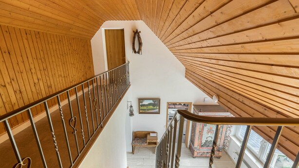 A wooden staircase with a metal railing, a wooden wall, a small seating area with a table, and a window with a view. - Apartment 'Ferienwohnung 2, 80qm' with Mountain View, Shared Garden and Wi-Fi (Rosswangen)