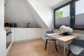 A modern kitchen with white cabinets, a wooden countertop, a black coffee maker, and a window with blinds. - Holiday Apartment "Casa Caso - 5" with Shared Terraces & Wi-Fi (Achim)
