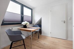A modern room with a table, two chairs, a window with blinds, a radiator, and a door. - Holiday Apartment "Casa Caso - 5" with Shared Terraces & Wi-Fi (Achim)