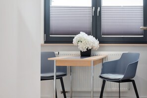 Ein Zimmer mit Tisch, zwei Stühlen, einer Heizung und einem Fenster mit Jalousien.