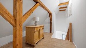 Eine Holztreppe mit einer weißen Wand und einem Schrank mit einer Lampe.