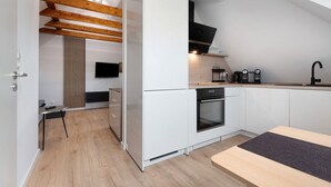 Eine moderne Küche mit weißen Schränken, einem eingebauten Backofen, einer Kaffeemaschine und einem Holzbalken an der Decke.
