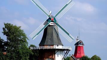 A windmill with a white and red structure, surrounded by trees.