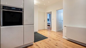 Una cocina moderna con electrodomésticos integrados, piso de madera y vista al salón.