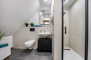 Ein modernes Badezimmer mit Toilette, Waschbecken und Dusche.