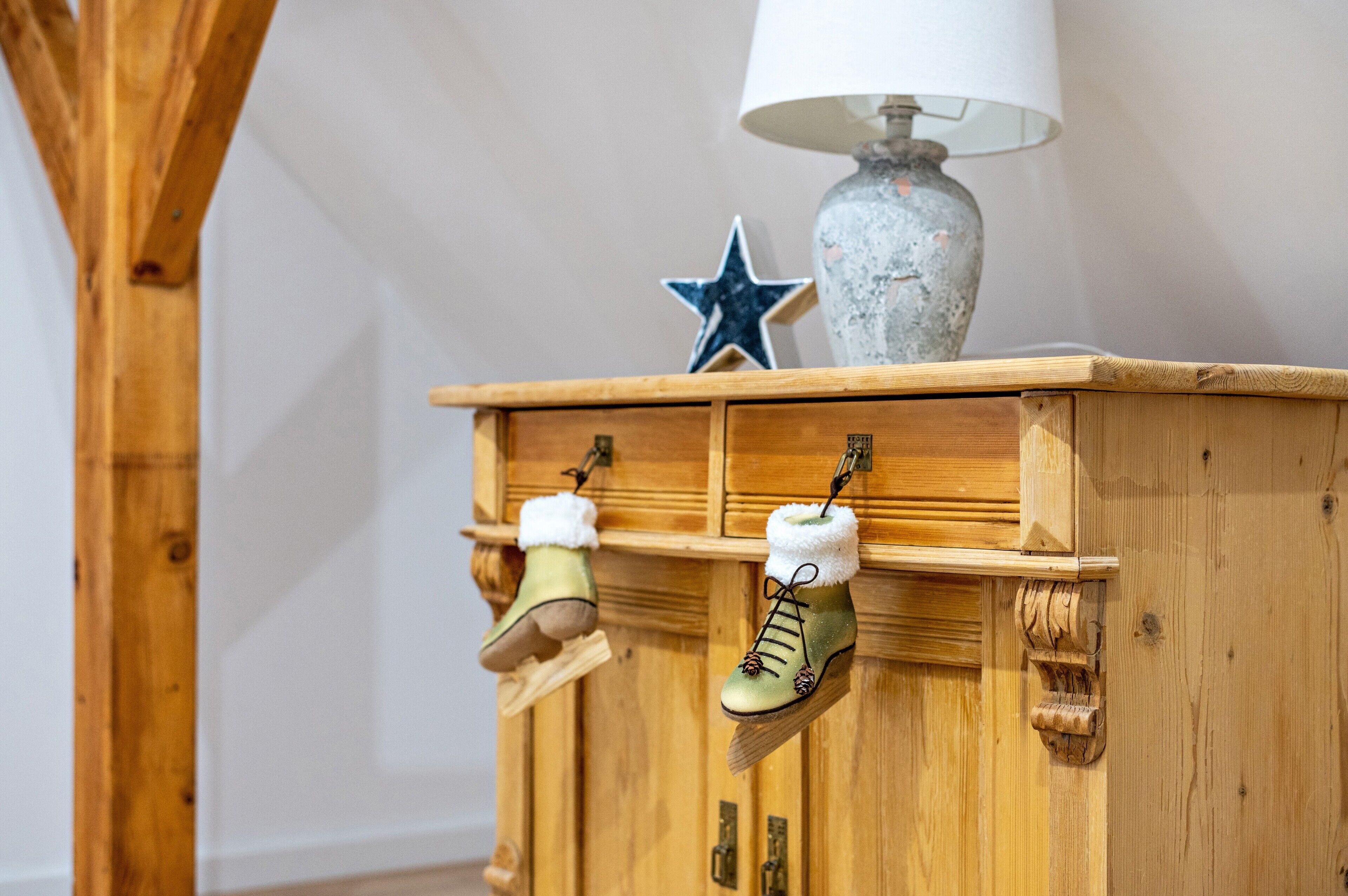 A wooden cabinet with two boots hanging on hooks, a star decoration, and a lamp on top.
