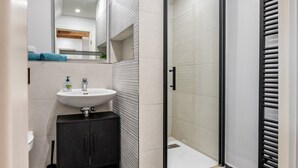 Un baño moderno con cabina de ducha de vidrio, un lavamanos y un armario.