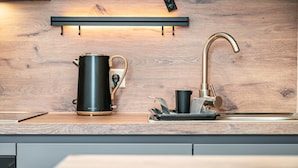 Una cocina moderna con hervidor, cafetera y lavabo.