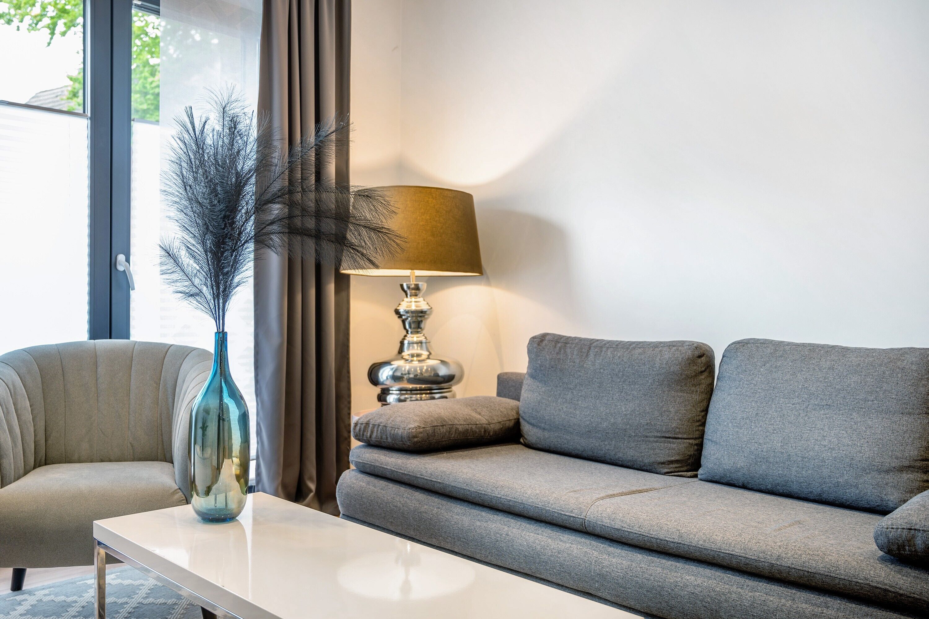 Un salon moderne avec un canapé, une table, une lampe et un vase.