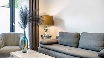 Un salon moderne avec un canapé, une table, une lampe et un vase.