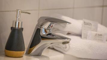 Ein Badezimmer mit einem modernen Wasserhahn, einer Seifenspender und einem Handtuchhalter mit Handtüchern.