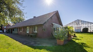 A brick house with a sloped roof, a covered patio, and a greenhouse. - Apartment with Conservatory near Movie Park, Private Terrace, and Wi-Fi (Bottrop)