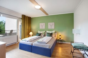 A bedroom with a bed, bedside tables, a window with curtains, and artwork on the wall.