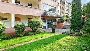 Un edificio a più piani con un giardino curato, un ingresso coperto e una scala che conduce all'ingresso.