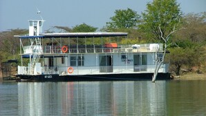A riverboat with a covered upper deck, lifebuoys, and a sign reading "Sundowner 25 PAX". - Houseboat With Aircon and Splash Pool - 2128 (Kariba)