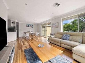 A modern living room with a wooden coffee table, a beige sofa, and a television.