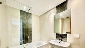 A modern bathroom with a glass-enclosed shower, a freestanding bathtub, and a vanity with a sink and mirror. - Elyssa Superbe Appartement aux Jardins de Carthage (Tunis)