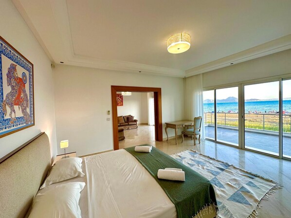 A hotel room with a bed, a desk, a chair, and a view of the beach. - Omnya Carthage Frontsea Luxury Villa (Carthage)