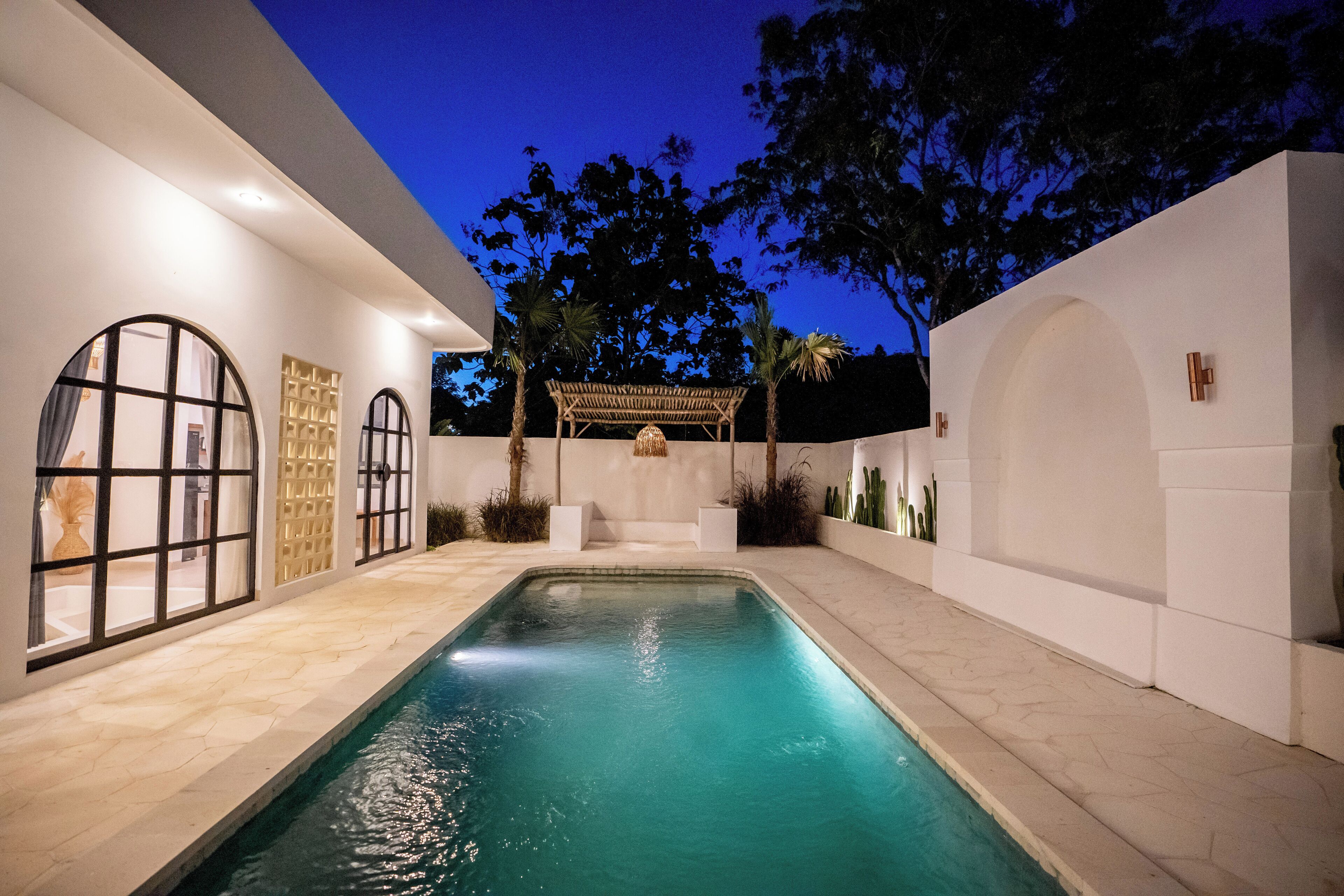 A swimming pool with a pergola and palm trees in a modern outdoor setting.