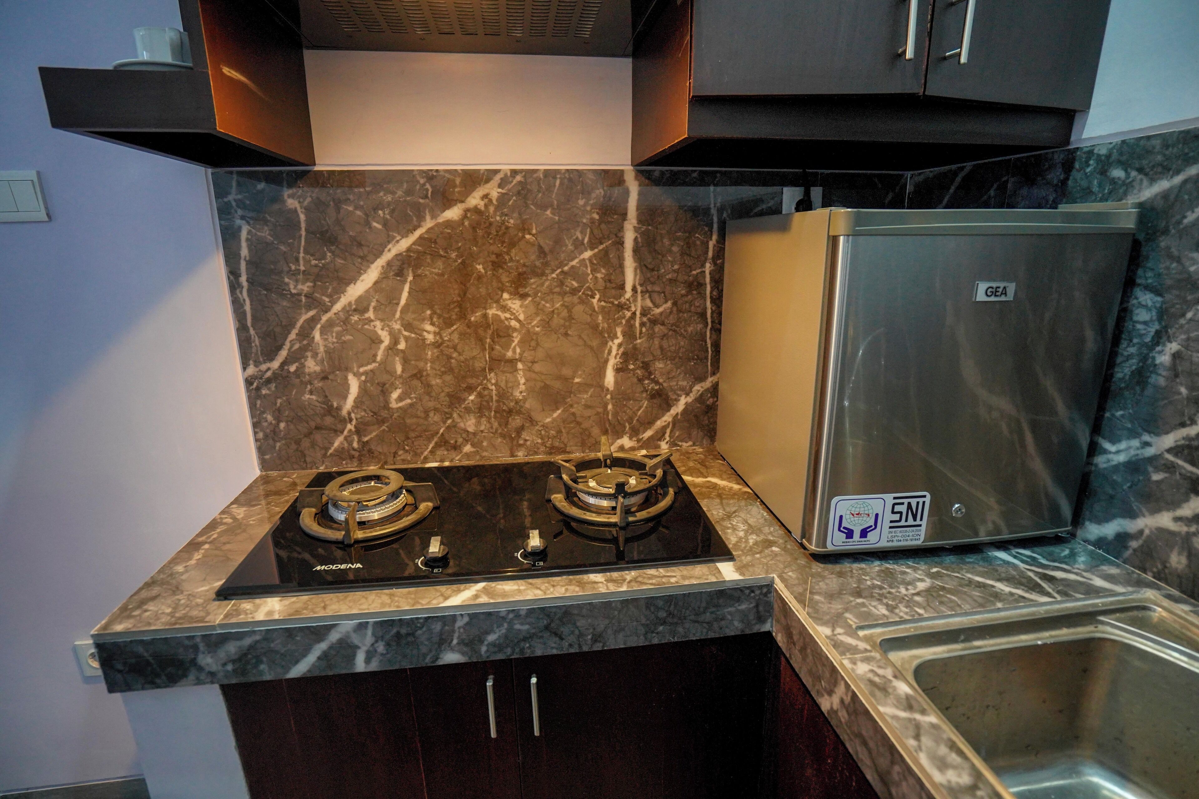 A kitchen with a gas stove, a stainless steel refrigerator, and a marble backsplash.