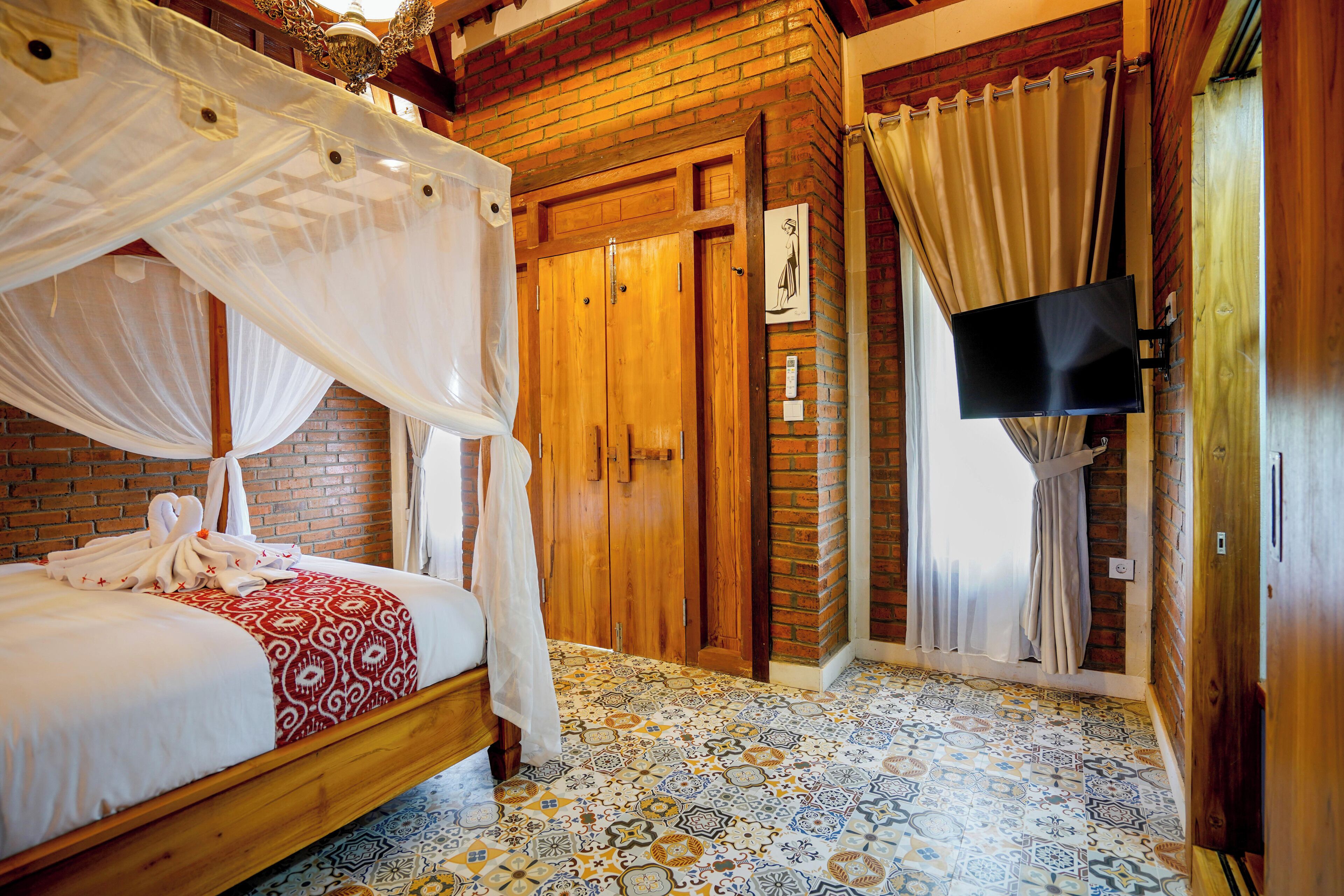 A room with a four-poster bed, a wooden wardrobe, a flat-screen TV, and a patterned floor.