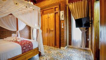 A room with a four-poster bed, a wooden wardrobe, a flat-screen TV, and a patterned floor.