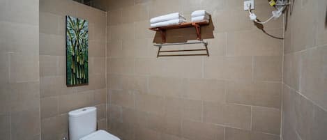 A bathroom with a toilet, a towel rack, and a wall-mounted painting.