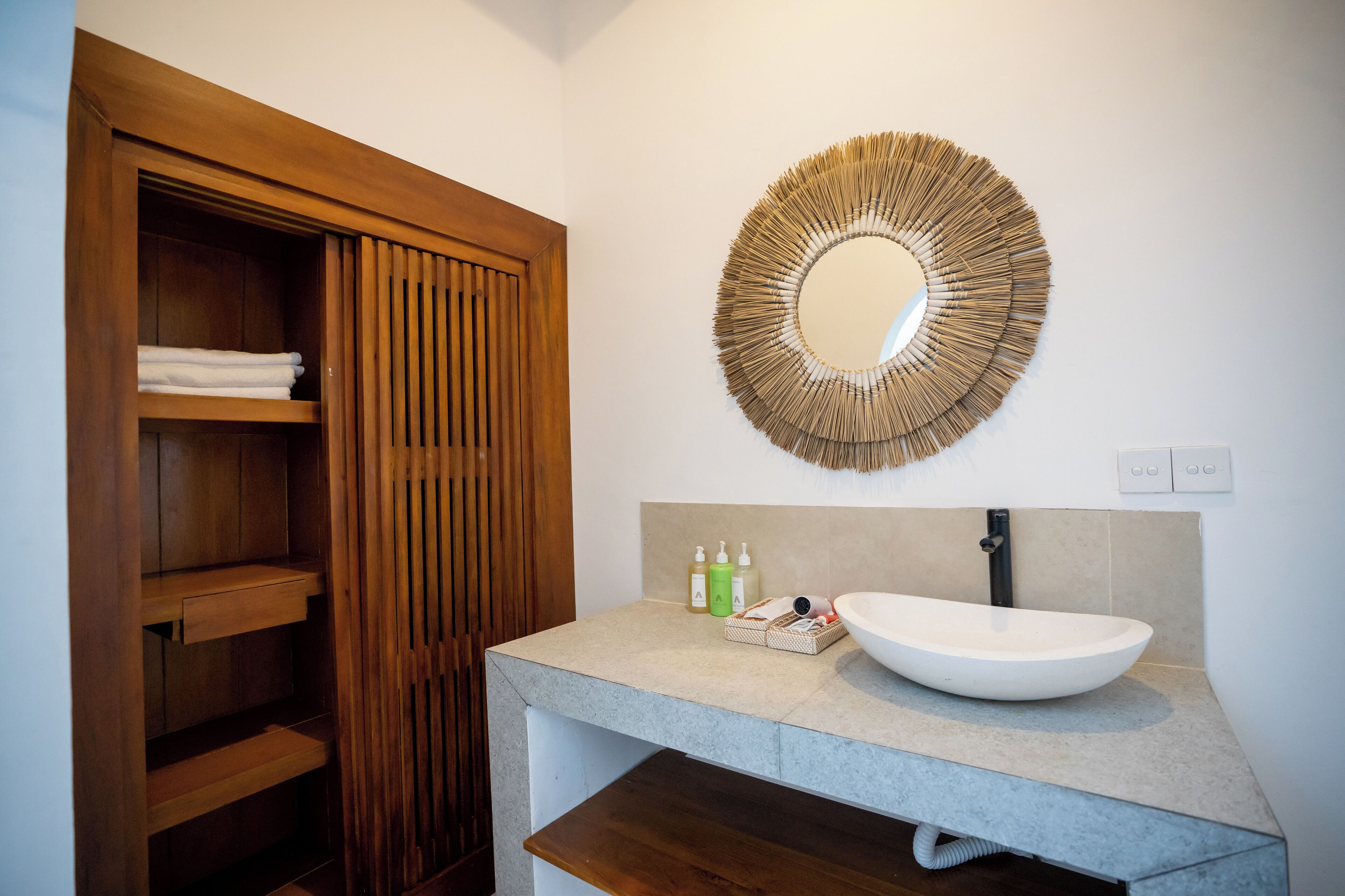 A bathroom with a wooden vanity, a large mirror, and a sink.