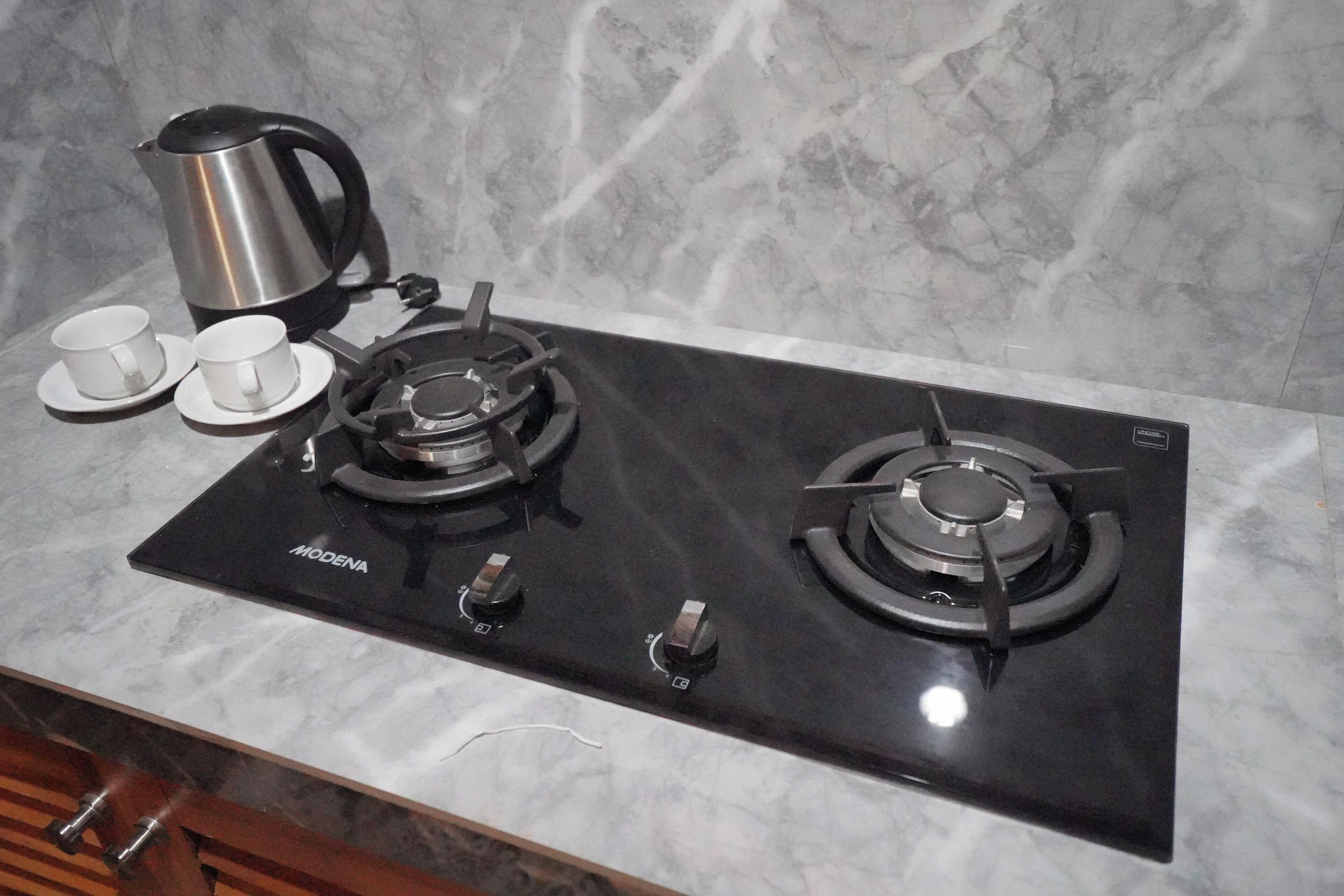 Een keuken met een zwart fornuis, twee kookplaten en een koffiezetapparaat.
