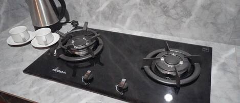 A kitchen with a black stove, two burners, and a coffee maker.