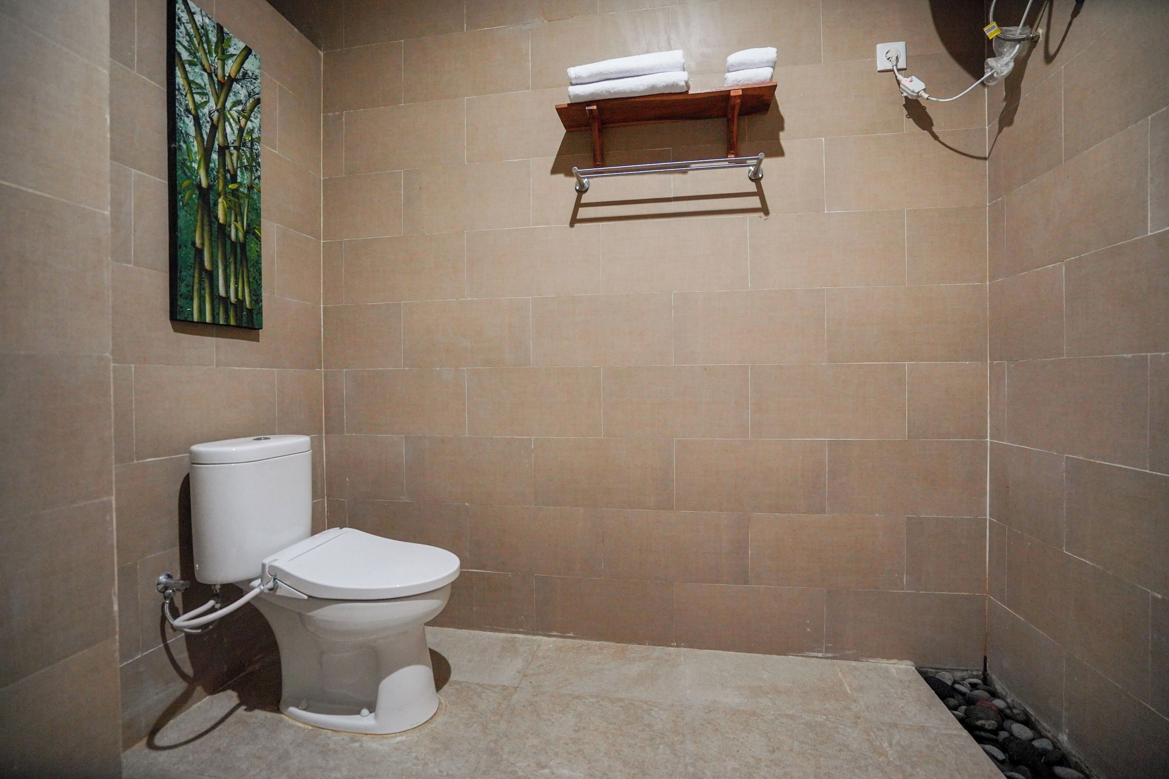 A bathroom with a toilet, a towel rack, and a painting on the wall.