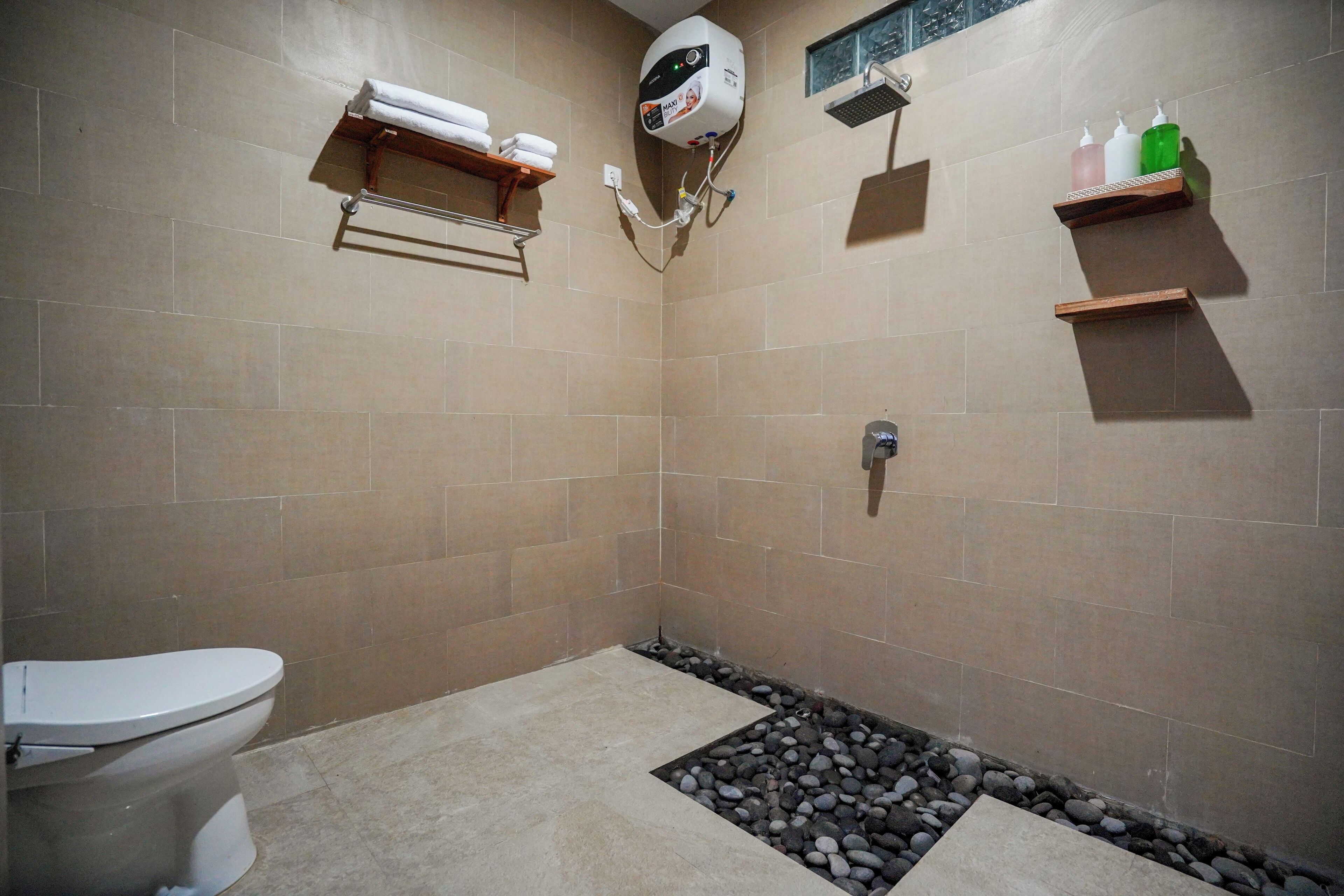 Een badkamer met toilet, douche en een klein plankje met toiletartikelen.