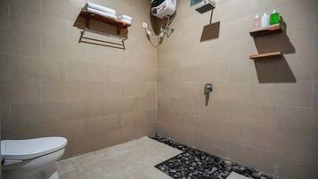 Een badkamer met toilet, douche en een klein plankje met toiletartikelen.