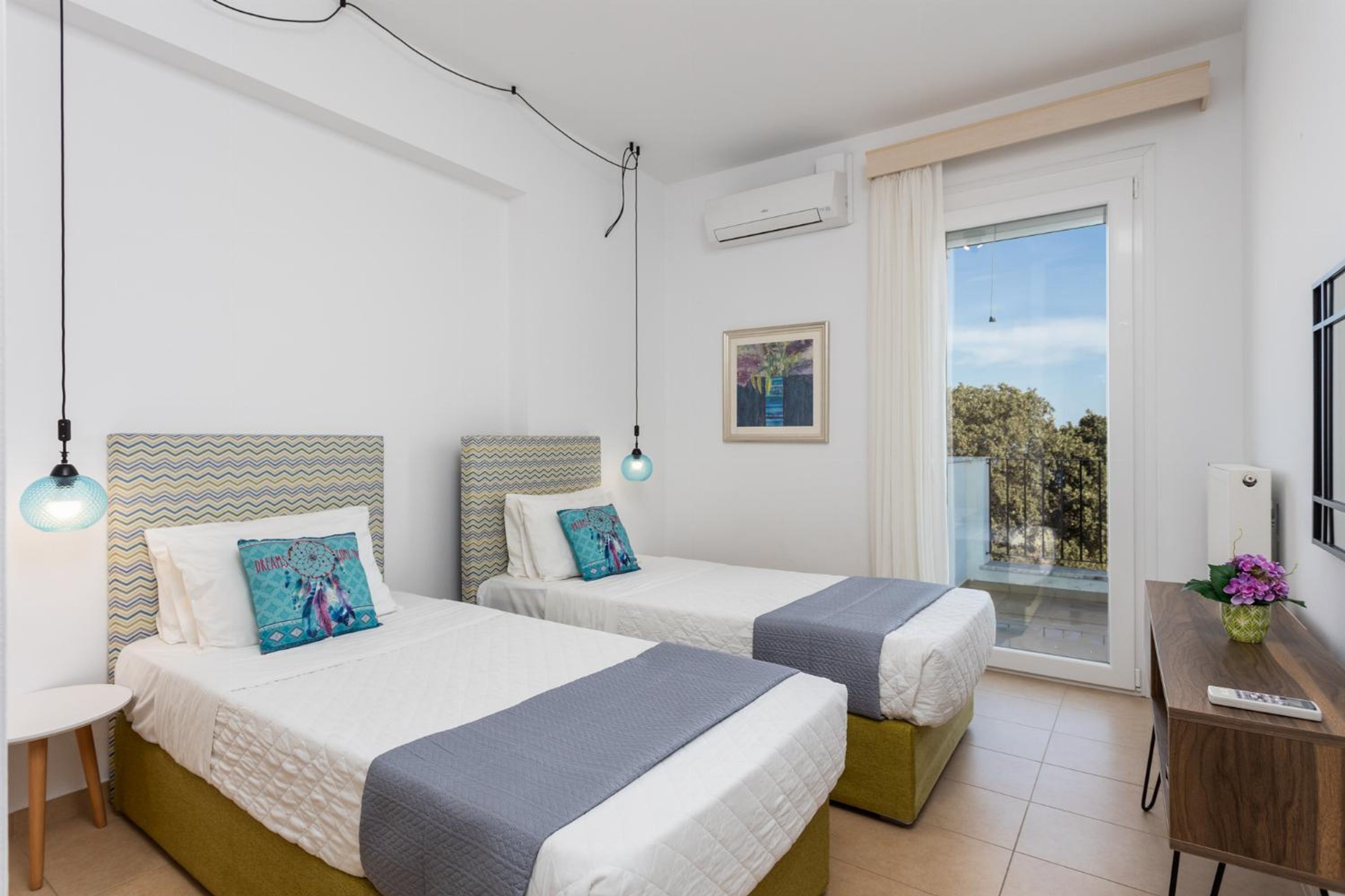 Hotelkamer met twee bedden, een bureau, een stoel, een balkon met uitzicht en een airconditioning.