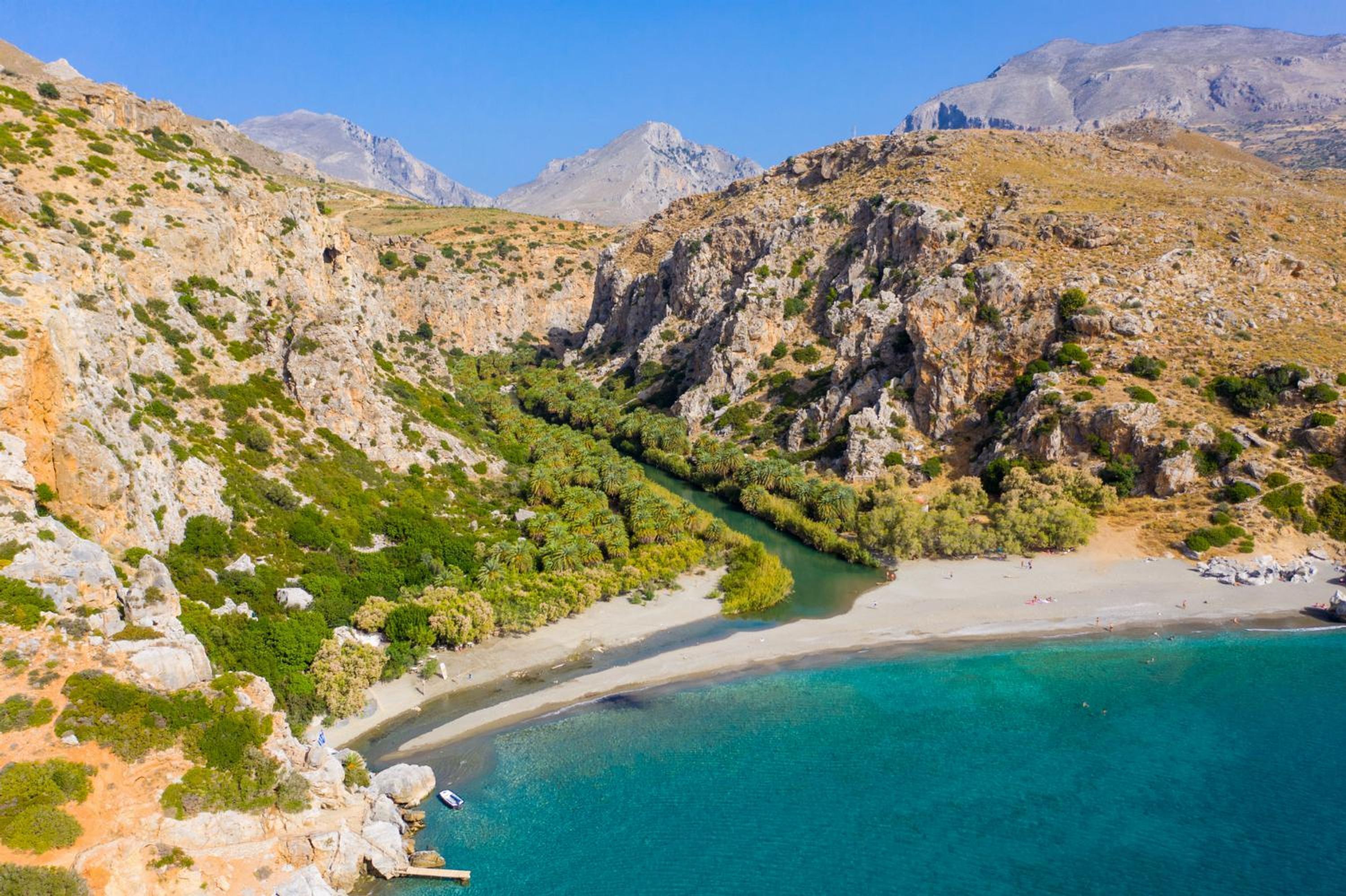 A coastal landscape with rocky terrain, a beach, and clear turquoise waters.