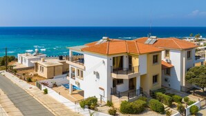 Un edificio a due piani con tetto in tegole rosse, pareti bianche e balconi affacciati sul mare.