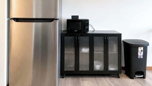 A kitchen with a stainless steel refrigerator, a microwave, a black cabinet, and a trash bin. - Stand Rock Studios in Wisconsin Dells! (Wisconsin Dells)