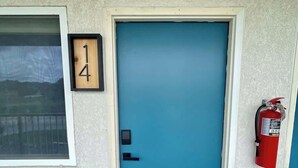 A blue door with a number '14' sign, a fire extinguisher, and a window with a metal grill. - Stand Rock Studios in Wisconsin Dells! (Wisconsin Dells)