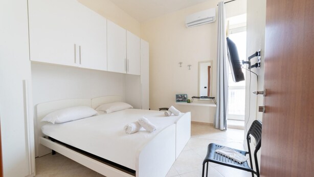 Un dormitorio moderno con una cama, una silla y un baño visible a través de una puerta abierta.