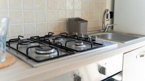 Una cocina con estufa a gas, un lavamanos y un armario.