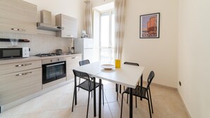 Cocina moderna con comedor, que incluye una mesa blanca, sillas negras y un cuadro con una imagen de un edificio.
