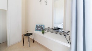 Un baño con un lavabo blanco, un espejo y un taburete negro.